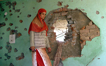 A Kashmiri woman walks past her destroyed house