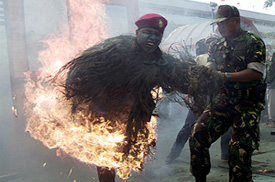 An Indonesian soldier tries to save his colleague who was struck by a projectile