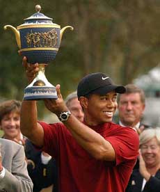 Tiger Woods smiles as he holds up the Gene Sarazen Cup after winning the American Express Championship