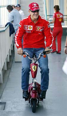 Ferrari's Michael Schumacher rides on a scooter