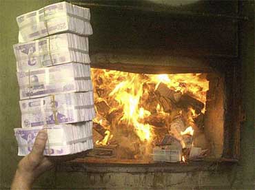 A pile of old Iraqi 25,000 dinar notes bearing the portrait of former Iraqi leader Saddam Hussein is thrown into a furnace