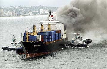 Tugs spray water onto a container ship