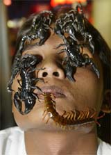 Scorpions and a centipede crawl on the face of Boontawee Siengwong