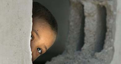 A Palestinian boy peeps out from inside his damaged family house after it was destroyed during an Israeli operation
