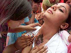 An artiste puts mehndi imprint on the throat of a girl on the eve of Karva Chauth in Patiala 