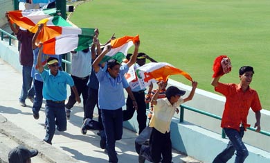 Excited cricket fans run across the PCA pavilion