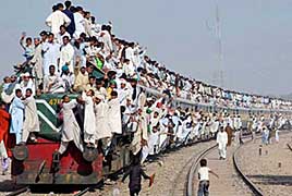 People cling to a train as they return to their homes in Multan