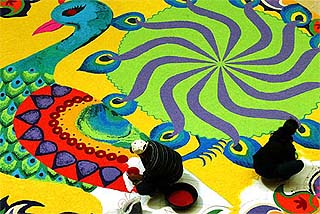 Two persons prepare a Kolum, an ancient Indian intricate art form, using coloured grains of rice, in Kuala Lumpur 