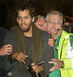 US illusionist David Blaine is assisted as he leaves his perspex box which was suspended from a crane near Tower Bridge