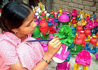 A girl gives final touches to clay temples 
