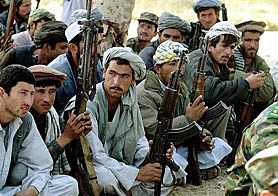 Afghan militiamen wait to turn in their weapons at a military base in Kunduz