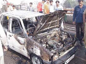 People look at the car that caught fire on the Jagraon bridge