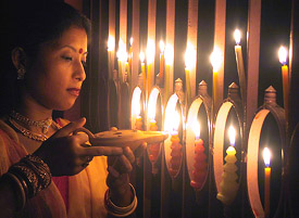A woman decorates her house with candles ahead of Divali