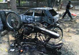The charred remains of a car and a motorcycle are seen at the site of the clash in Bali
