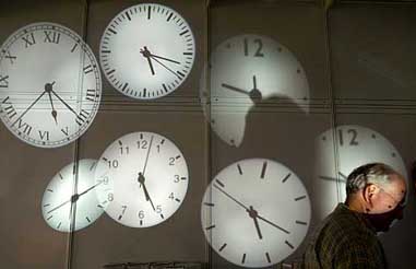 A man stands in front of projected images of clocks at the British booth of Hong Kong International Lighting Fair