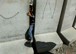 A Palestinian boy tries to pass through a gap on a concrete wall, separating the West Bank town of Abu Dis from East Jerusalem