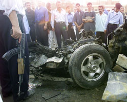 Iraqi policemen and civilians look at the remains of a suicide bomber's car in Falluja 