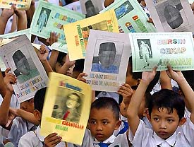 Children wave pictures of outgoing Malaysian Prime Minister Mahathir Mohamad at Putrajaya