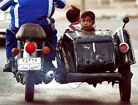 Tow boys ride home in a motorcycle sidecar for the evening Ramzan meal in Baghdad