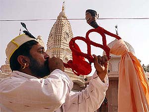 A devotee blows a traditional instrument on the eve of Rudra Maha Yag