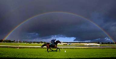 Irish jockey David Condon rides past a rainbow during a track workout