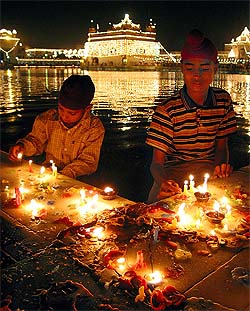 Two boys light candles outside the Golden Temple on the eve of Gurpurb