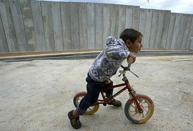 A Palestinian boy rides his bike on the terrace of his family's home