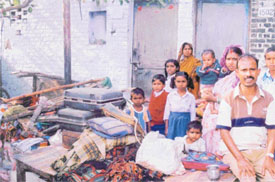 Evicted migrant labourers of EWS Colony sit with their families and belongings on a road 