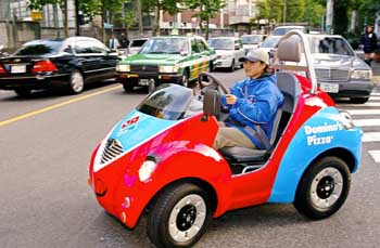 A Domino Pizza shop employee drives an electric vehicle named �Qi�, produced by Japanese toy-maker Takara, to deliver pizzas in Tokyo on Friday.