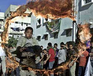A Palestinian boy jumps through a blazing ring at a rally in Gaza City 