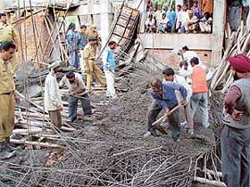 Fire-brigade personnel and labourers look for injured persons buried under the debris of the roof at Law Bhavan 
