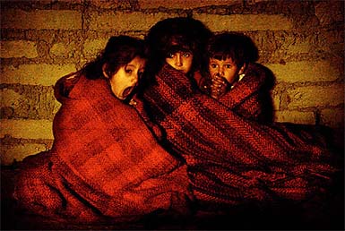 Terrified Iraqi children protect themselves from the cold after they're taken outside their house during a pre-dawn raid in a suburb of Baquba