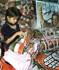 A girl counts poll campaign banners of the Congress inside a workshop in Ahmedabad 