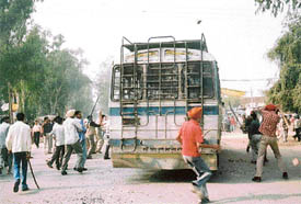 Agitating students wielding lathis follow a bus while protesting against the death of a student in jagraon