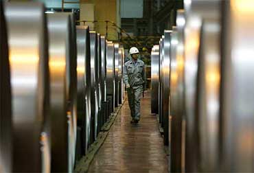 A worker walks past rolls of tin plate at a Baosteel plant on the outskirts of Shanghai 