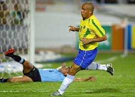 Brazilian striker Ronaldo celebrates after scoring a goal as Uruguay defender Diego Lopez lies on the ground 