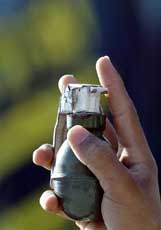 A masked Palestinian militant holds up a hand grenade as he parades in the Jabalya refugee camp in the northern part of Gaza Strip