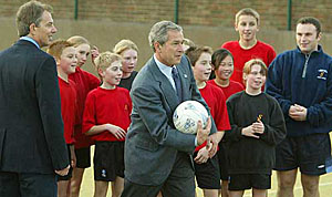 US President George W. Bush throws a ball as British Prime Minister Tony Blair looks on