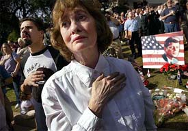 A lady listens to the national anthem of America on the 40th anniversary of the assassination of President John F. Kennedy