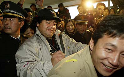 Argentinean soccer legend Diego Armando Maradona signs an autograph on the back of a fan upon his arrival in Shanghai 