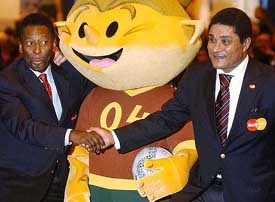 Soccer legends Pele of Brazil and Eusebio of Portugal strike a pose next to the Euro 2004 mascot 'Kinas' during the opening of a football fair in Lisbon
