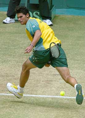 Australia's Mark Philippoussis plays a shot between his legs on his way to win the reverse singles match against Spain's Juan Carlos Ferrero