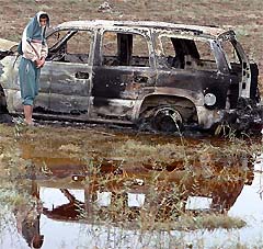 An Iraqi youth stands near a burned out car a day after a deadly attack on Spanish troops, in Baghdad on Sunday