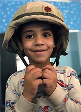 An Iraqi orphan boy wears the helmet of US Major Bobby Hart in the southern Iraqi town of Nassariya