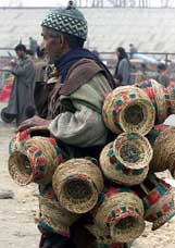 A Kashmiri Muslim carries firepots or kangris at a market in Srinagar 