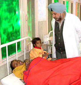 A medical specialist of Bathinda civil hospital attends on an AIDS patient Shinder Kaur, while her daughter is playing