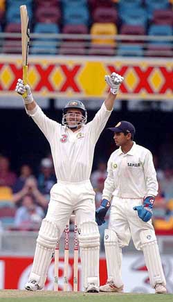 Australia's Justin Langer acknowledges his century as Indian wicketkeeper Parthiv Patel looks on the first day of the first Test 