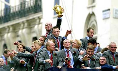 Members of the triumphant England 2003 Rugby World Cup squad wave to fans as they proceed through the capital during a parade to mark the team's victory, in London on Monday