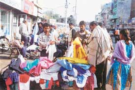 Customers flock to buy used clothes from a seller in a flea market