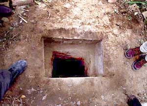 Journalists stand beside the spider hole in which Saddam Hussein was hiding when he was captured by the US troops on Saturday